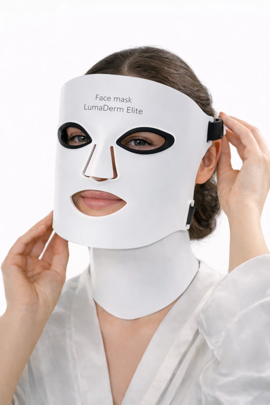 Woman wearing a white face mask with black eye and nose shapes, branded 'LumaDerm Elite'.